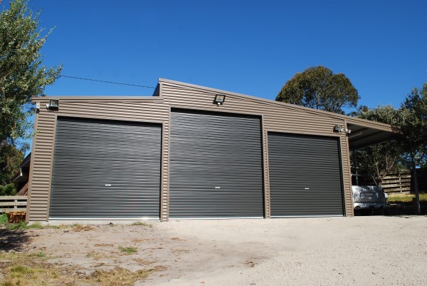 A triple  car skillion roof garage with a lean to and an additional 4th open bay to the right 