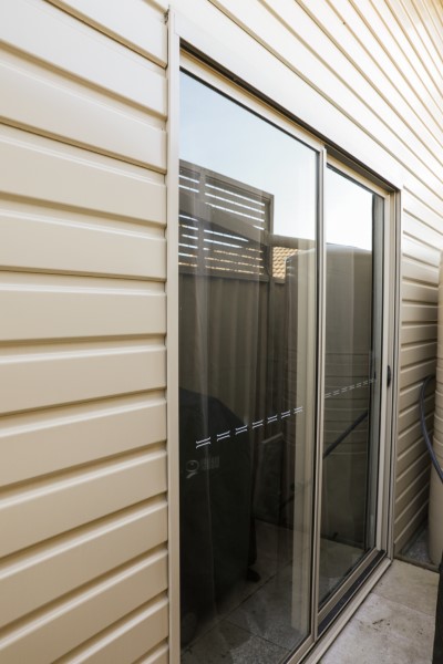 A glass sliding door set into an off white steel shed wall