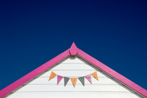 A white shed roof with a bold pink trim and colourful bunting