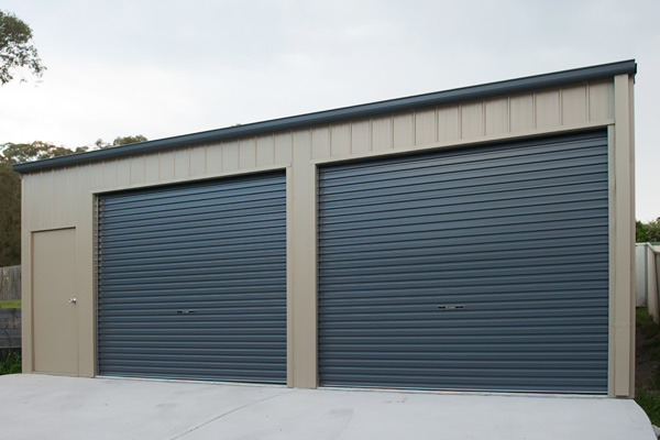 Double garage and boat shed with both blue roller doors closed and a personal access door to the left