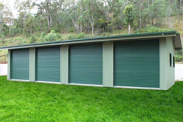 Green shed with four roller doors along front and a bright green lawn